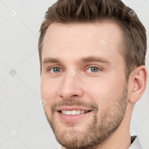 Joyful white young-adult male with short  brown hair and grey eyes