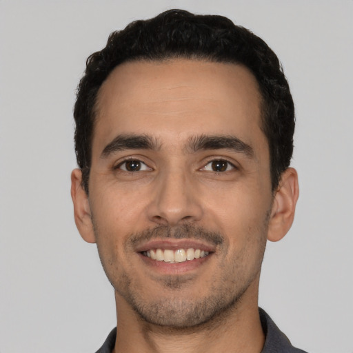 Joyful latino young-adult male with short  black hair and brown eyes