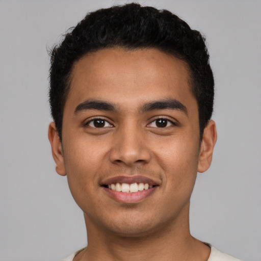 Joyful latino young-adult male with short  black hair and brown eyes