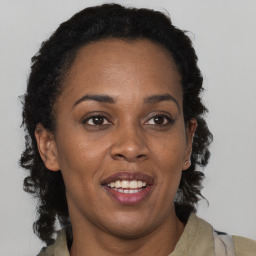 Joyful black adult female with long  brown hair and brown eyes