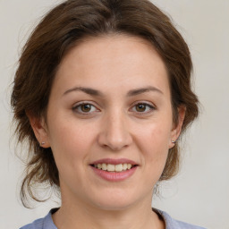 Joyful white young-adult female with medium  brown hair and green eyes