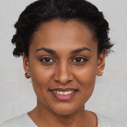 Joyful black young-adult female with short  brown hair and brown eyes