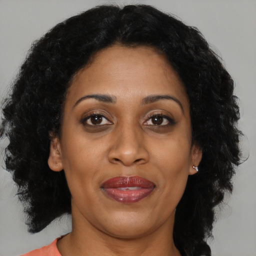 Joyful black adult female with long  brown hair and brown eyes