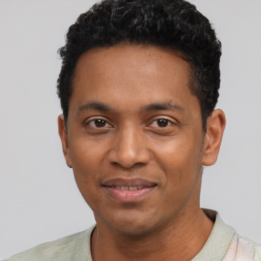 Joyful black young-adult male with short  black hair and brown eyes