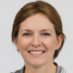 Joyful white young-adult female with medium  brown hair and grey eyes