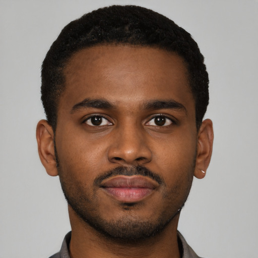 Joyful black young-adult male with short  brown hair and brown eyes