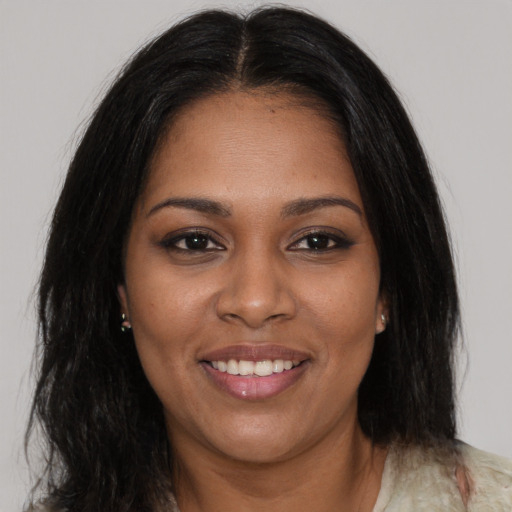 Joyful black young-adult female with long  brown hair and brown eyes