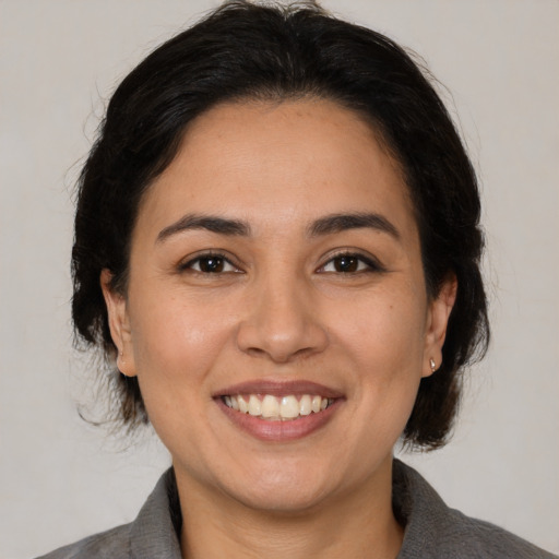 Joyful latino adult female with medium  brown hair and brown eyes