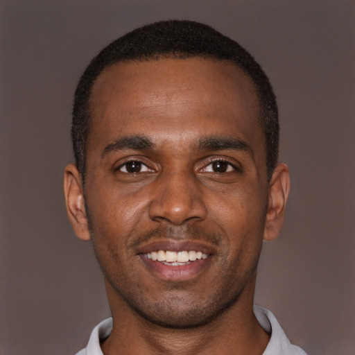 Joyful black young-adult male with short  brown hair and brown eyes