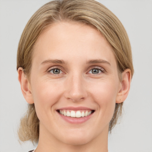 Joyful white young-adult female with medium  brown hair and grey eyes