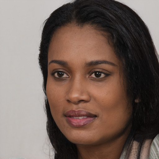 Joyful black young-adult female with long  black hair and brown eyes