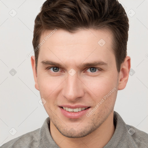 Joyful white young-adult male with short  brown hair and grey eyes