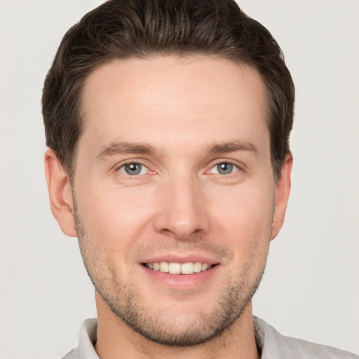 Joyful white young-adult male with short  brown hair and grey eyes