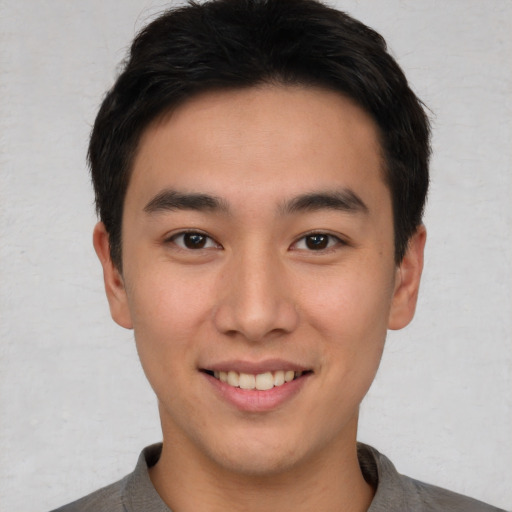 Joyful asian young-adult male with short  brown hair and brown eyes