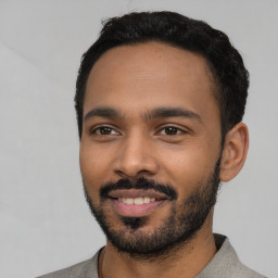 Joyful latino young-adult male with short  black hair and brown eyes