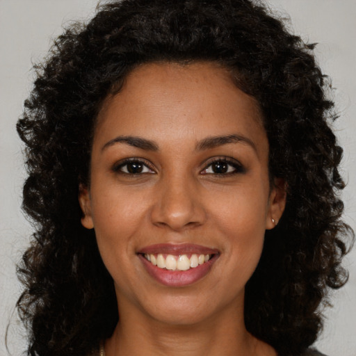 Joyful black young-adult female with long  brown hair and brown eyes