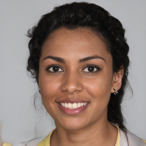 Joyful black young-adult female with long  black hair and brown eyes