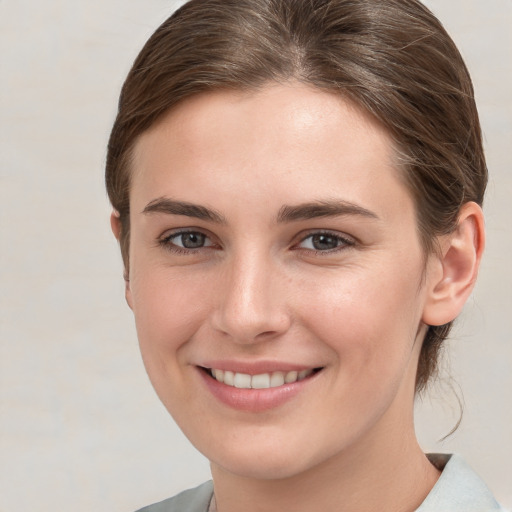 Joyful white young-adult female with medium  brown hair and grey eyes