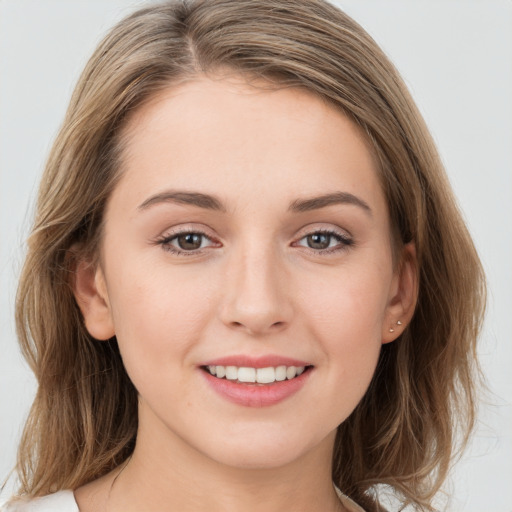 Joyful white young-adult female with medium  brown hair and grey eyes