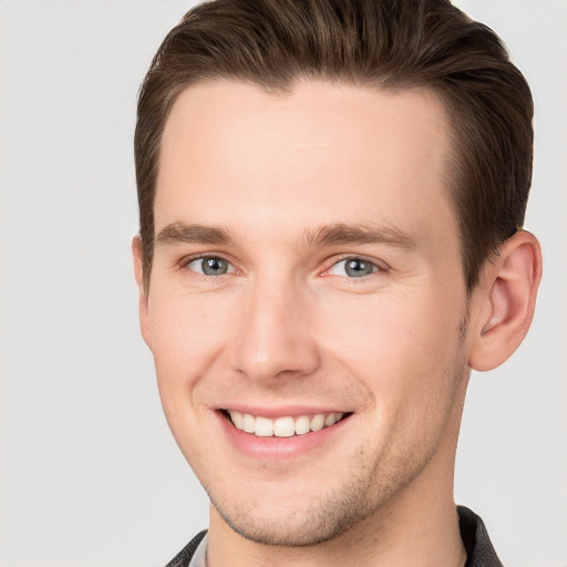 Joyful white young-adult male with short  brown hair and grey eyes