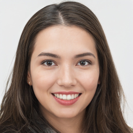 Joyful white young-adult female with long  brown hair and brown eyes