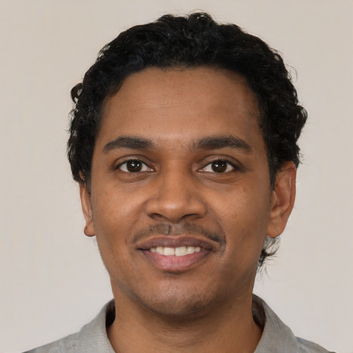 Joyful black young-adult male with short  black hair and brown eyes