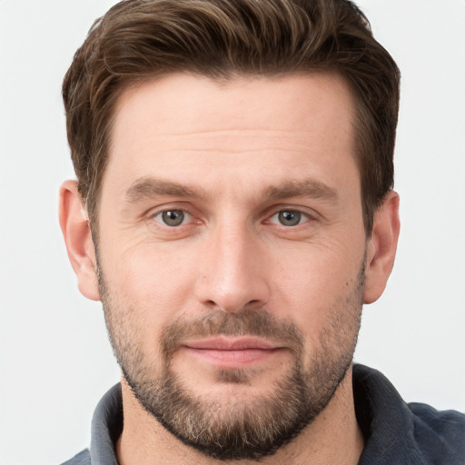 Joyful white young-adult male with short  brown hair and grey eyes