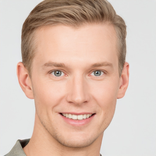 Joyful white young-adult male with short  brown hair and grey eyes