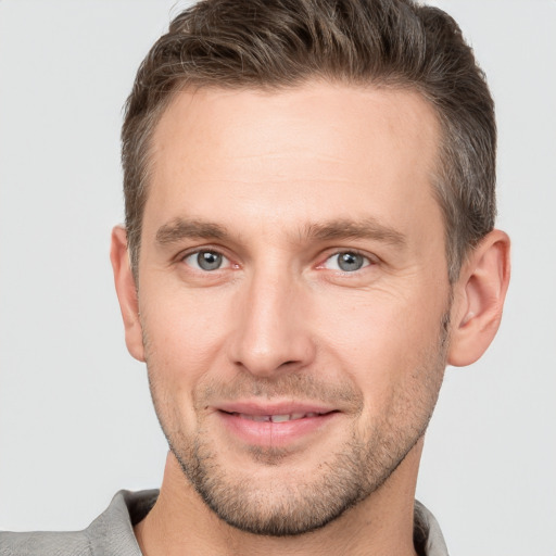 Joyful white young-adult male with short  brown hair and grey eyes