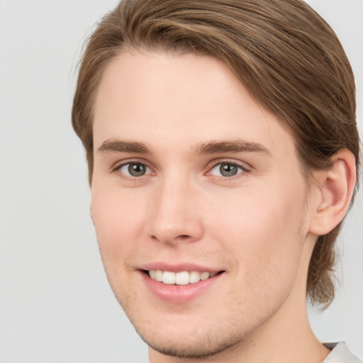 Joyful white young-adult male with short  brown hair and grey eyes