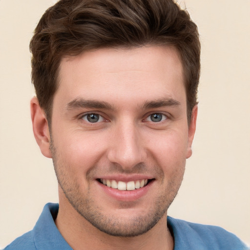 Joyful white young-adult male with short  brown hair and grey eyes