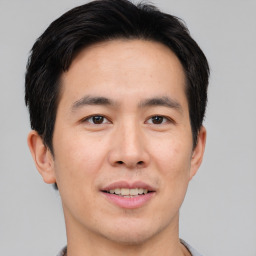 Joyful asian young-adult male with short  brown hair and brown eyes