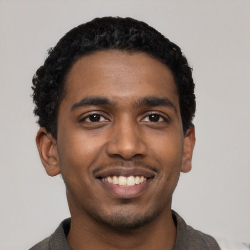 Joyful black young-adult male with short  black hair and brown eyes