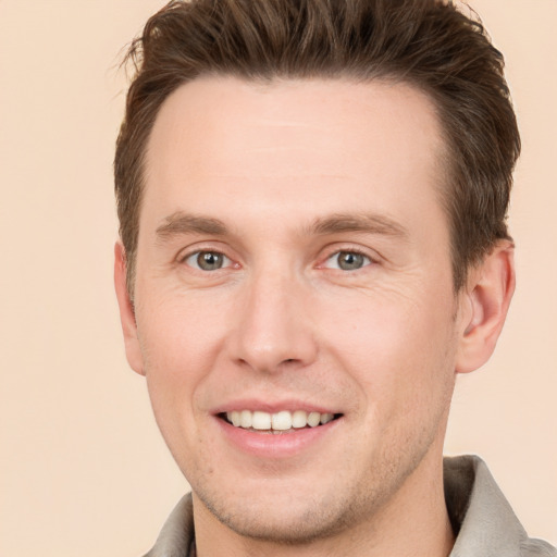 Joyful white young-adult male with short  brown hair and grey eyes