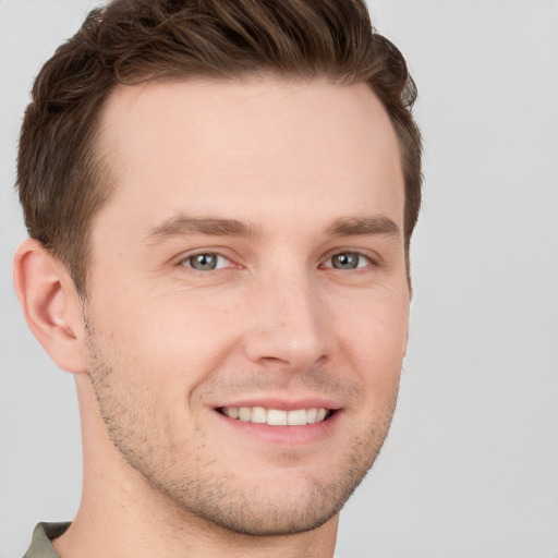 Joyful white young-adult male with short  brown hair and grey eyes