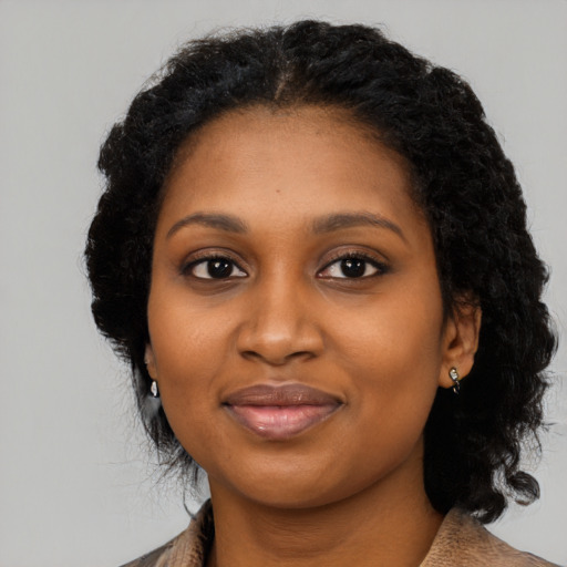 Joyful black young-adult female with long  black hair and brown eyes