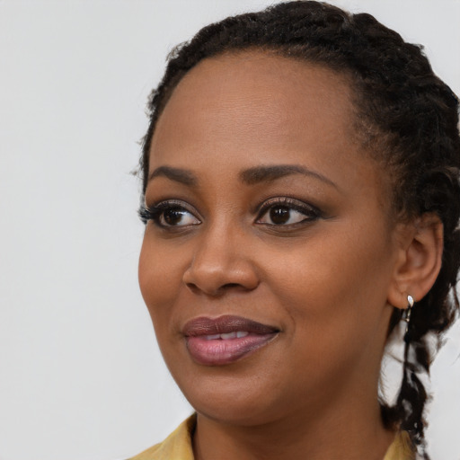 Joyful black young-adult female with long  brown hair and brown eyes
