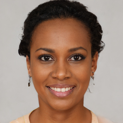 Joyful black young-adult female with short  black hair and brown eyes