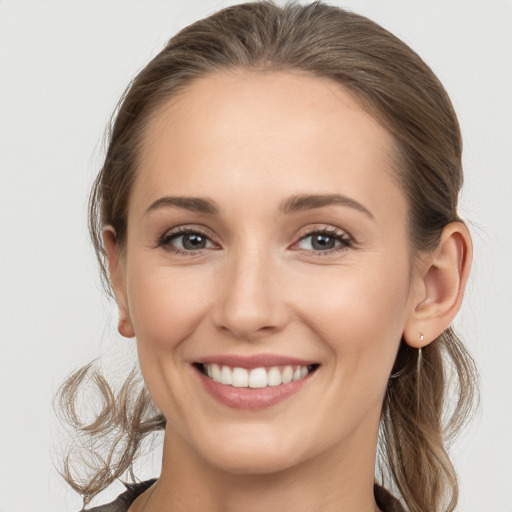 Joyful white young-adult female with medium  brown hair and grey eyes