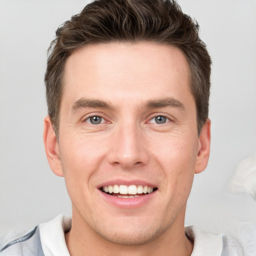 Joyful white young-adult male with short  brown hair and grey eyes