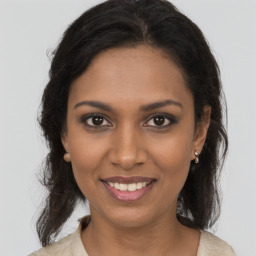 Joyful black young-adult female with long  brown hair and brown eyes