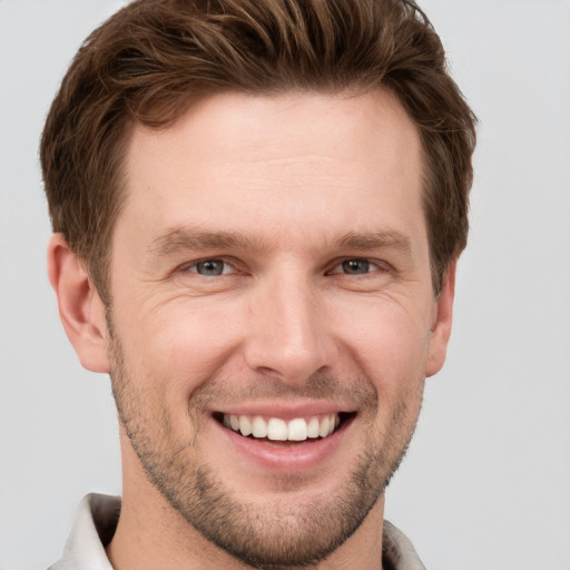 Joyful white young-adult male with short  brown hair and grey eyes