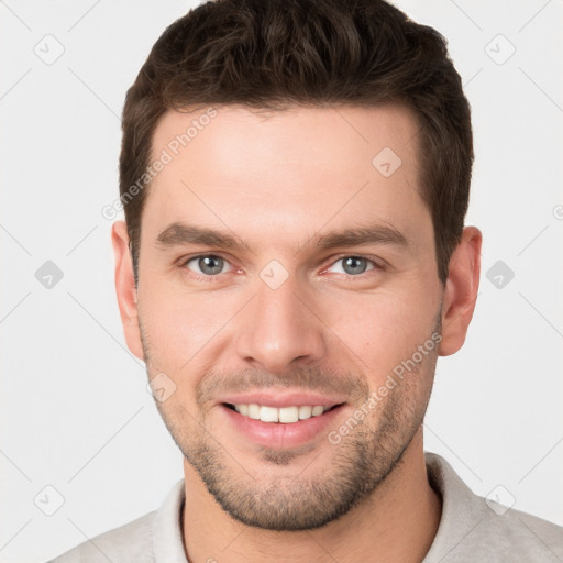 Joyful white young-adult male with short  brown hair and grey eyes