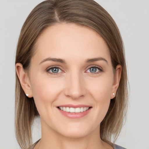 Joyful white young-adult female with medium  brown hair and grey eyes