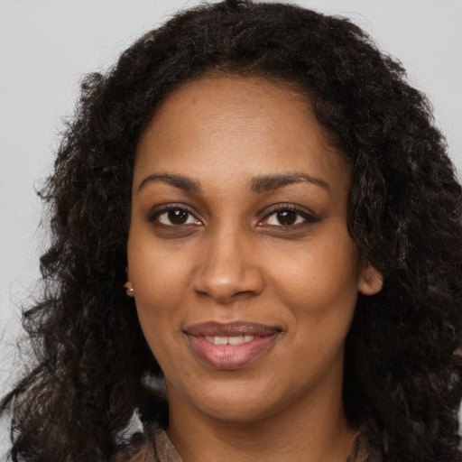 Joyful black young-adult female with long  brown hair and brown eyes