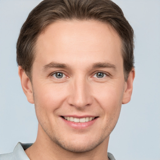 Joyful white young-adult male with short  brown hair and grey eyes