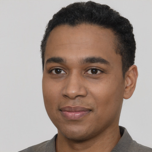 Joyful black young-adult male with short  black hair and brown eyes