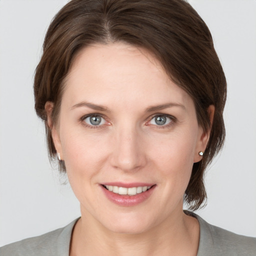 Joyful white young-adult female with medium  brown hair and grey eyes