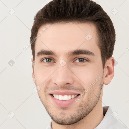 Joyful white young-adult male with short  brown hair and grey eyes