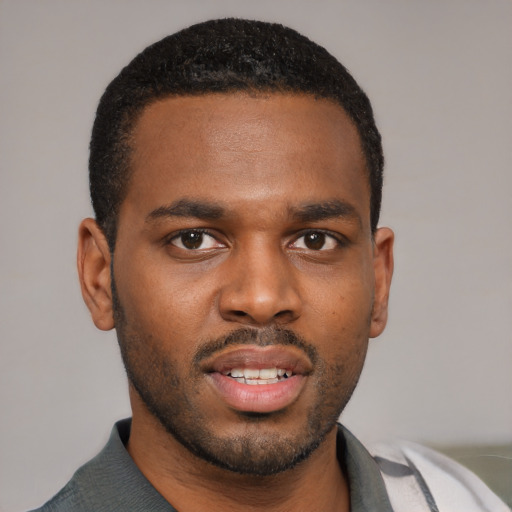 Joyful black young-adult male with short  black hair and brown eyes